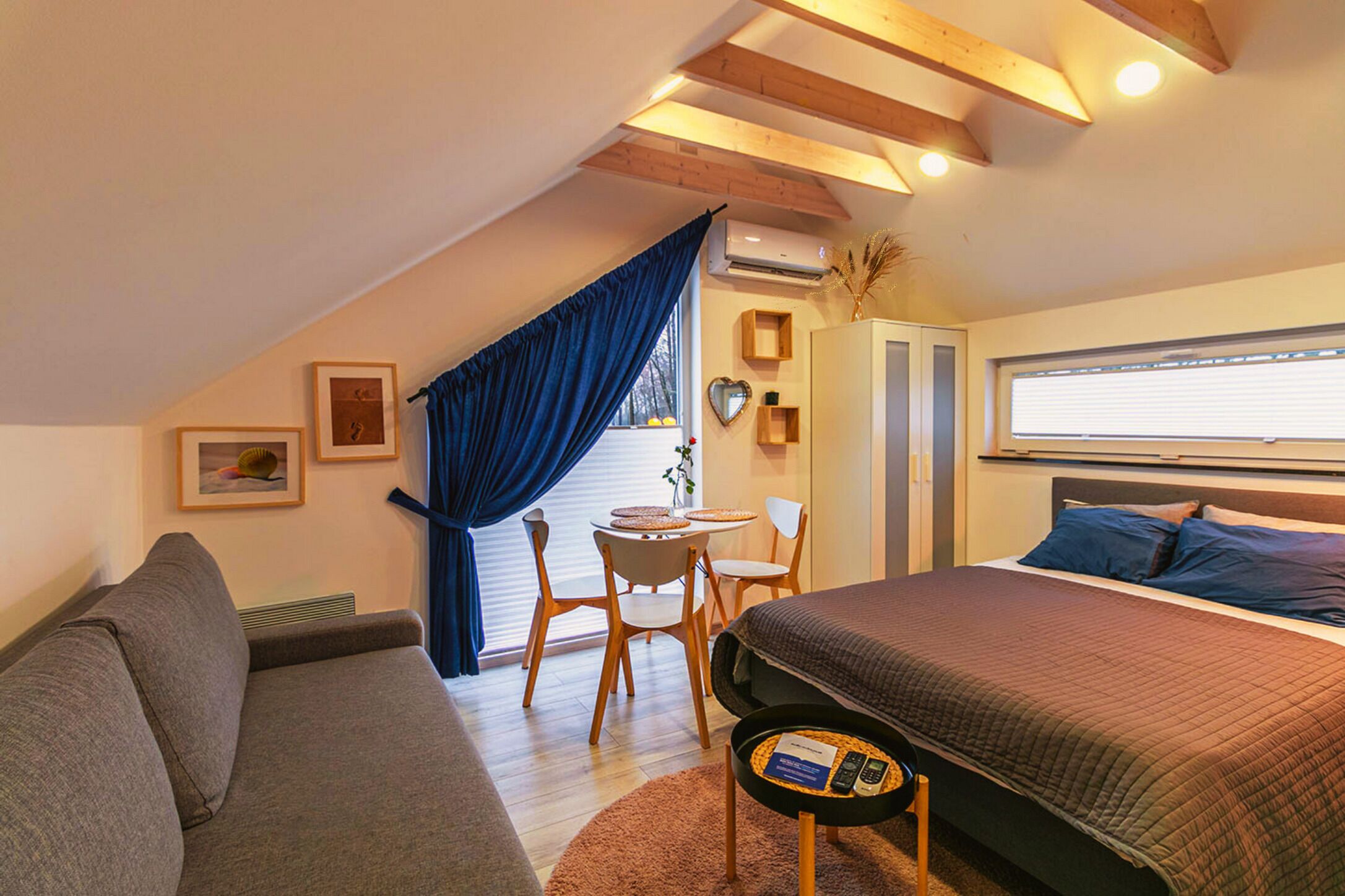 Una habitación acogedora con cama, sofá, una mesita y ventana con cortinas.