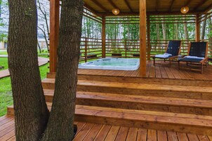Una terraza de madera con un jacuzzi y dos sillones de descanso.