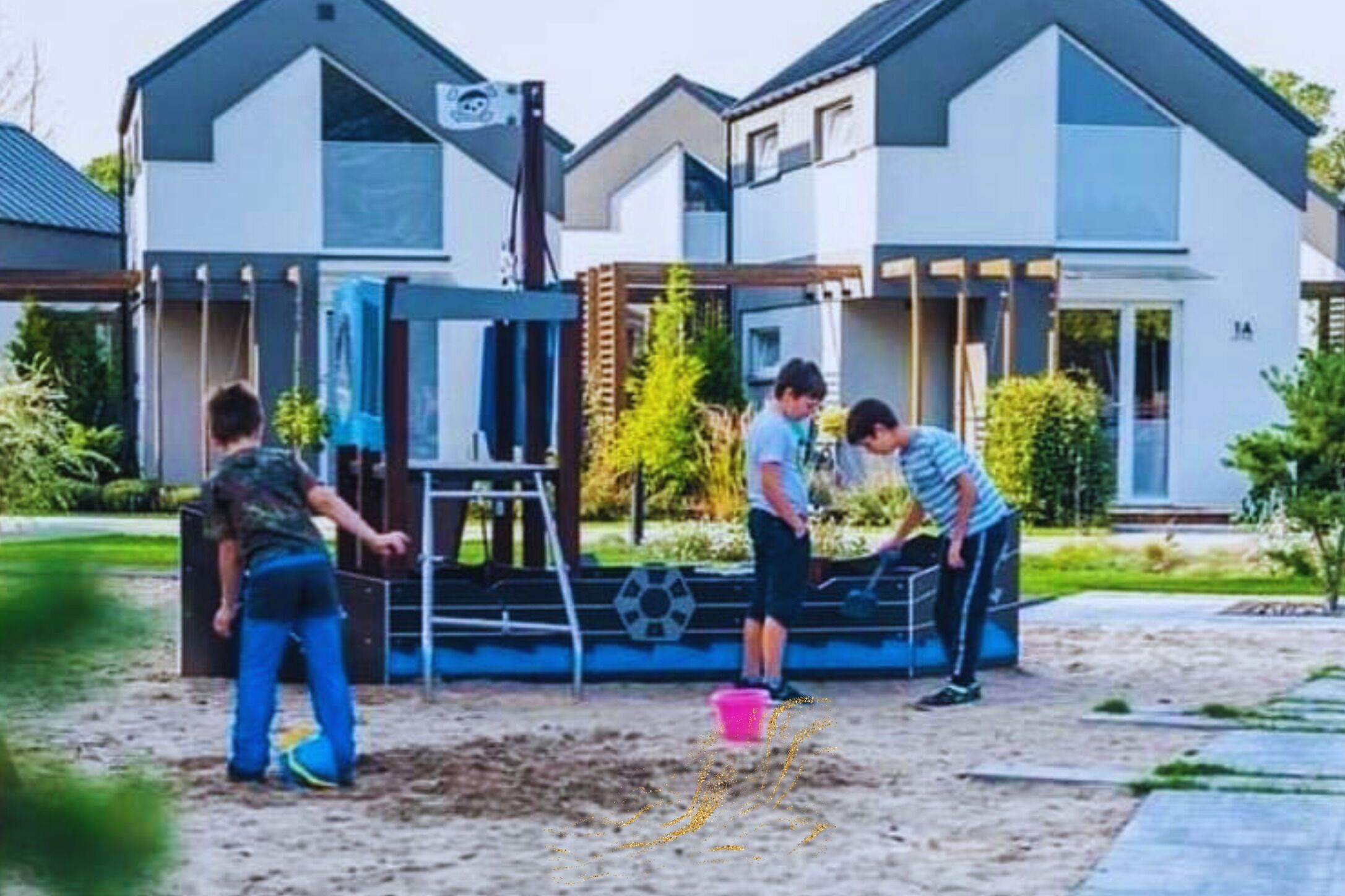 Un quartier résidentiel moderne avec des maisons, une aire de jeux et une zone sablonneuse.