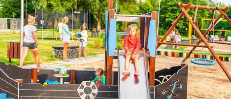 A playground with a slide, climbing structures, and a sandbox.