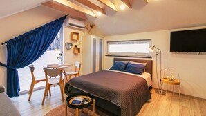 A bedroom with a bed, a desk, a chair, a TV, and a window with curtains. - Baltic Natur Park - Apartament B (Niechorze)