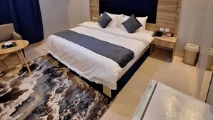 A modern hotel room with a large bed, a desk, a chair, and a small table. - agnehat alsmo hotel (Al Aydabi)