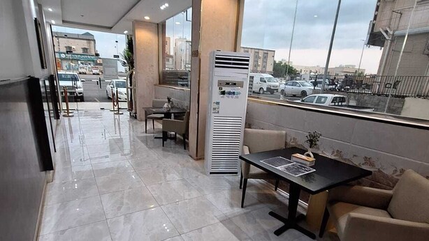 A modern indoor area with a long corridor, seating arrangements, and a large window overlooking a parking area. - agnehat alsmo hotel (Al Aydabi)
