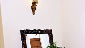 A mirror with an ornate frame, a small stool, and a potted plant.