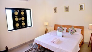 A neatly arranged hotel room with a bed, a laptop, and a window with a decorative screen.