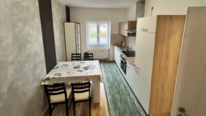 Et kompakt køkken med spisebord, stole, et vindue og et køleskab.