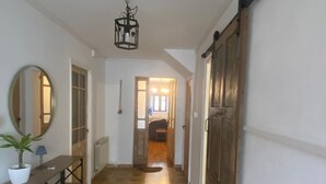 A hallway with patterned flooring, a potted plant, a mirror, and a sliding door.