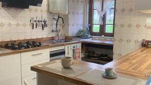 A kitchen with a central island, white chairs, a window with curtains, and a stove.