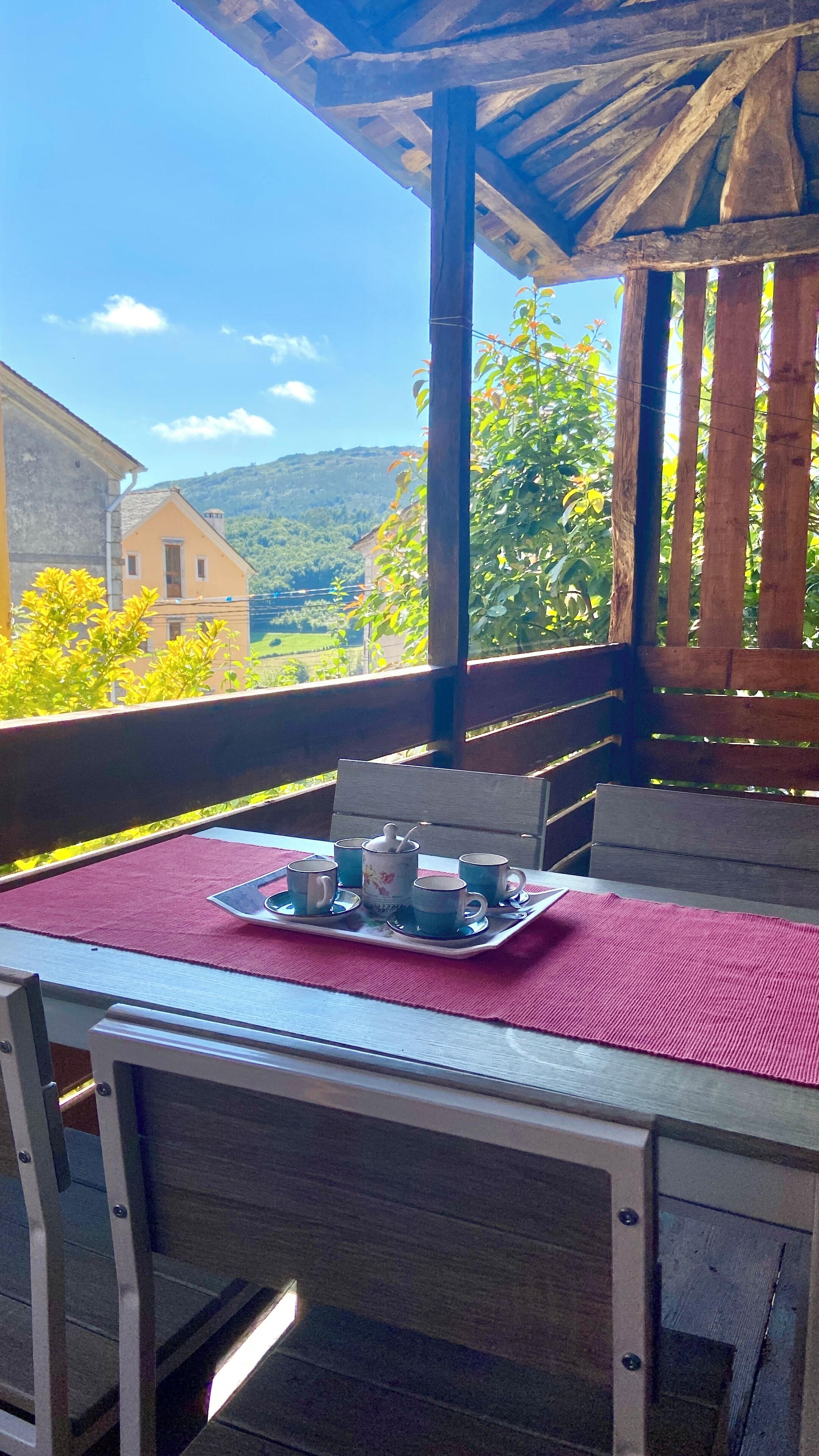 A wooden outdoor seating area with a table set for two, overlooking a scenic landscape.