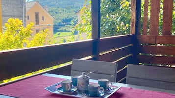 A wooden outdoor seating area with a table set for two, overlooking a scenic landscape.