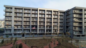 Un edificio residenziale a più piani con balconi, un cortile lastricato e un cartello che indica un ristorante.