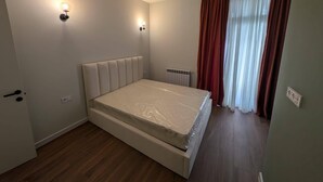 Una camera da letto con un letto, un termosifone e una finestra con tende.