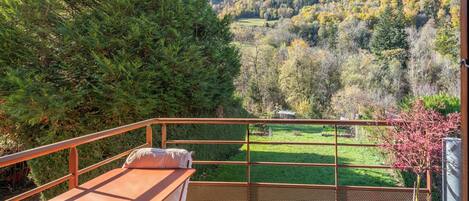 Ein Balkon mit Tisch und Stühlen mit Blick auf eine gebirgige Landschaft im Herbstlaub.