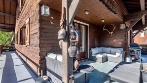A wooden cabin with a covered patio, outdoor seating, and a barbecue area. - Magnificent Demi-Chalet (THONES)