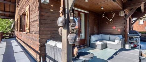 Une cabane en bois dotée d’un patio couvert, d’un espace salon extérieur et d’un coin barbecue.