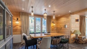 A cozy wooden interior with a dining table, chairs, and pendant lights. - Magnificent Demi-Chalet (THONES)