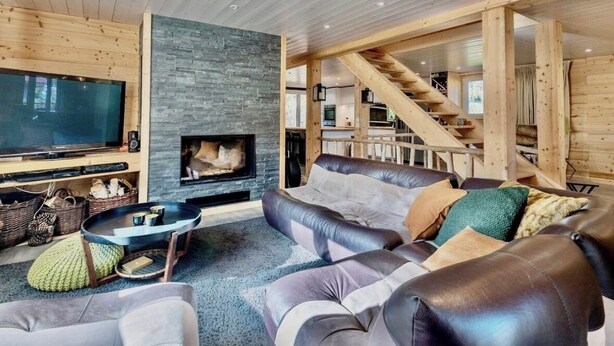 A modern living room with a fireplace, leather sofa, and a TV. - Magnificent Demi-Chalet (THONES)