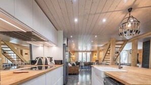 A modern kitchen with wooden beams, a central island, and a dining area with a view. - Magnificent Demi-Chalet (THONES)