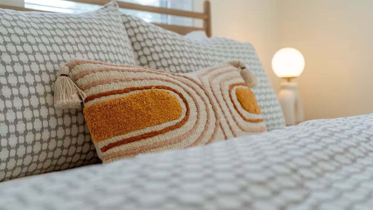 A bed with patterned pillows and a textured blanket.