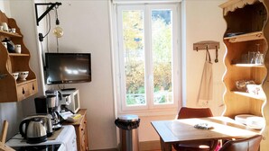 A compact kitchen with a washing machine, stove, and a TV on the wall. - Le Salers -Le Mont Dore 2pers (Mont-Dore)