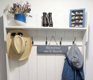 Eine Wandablage mit einem Schild, Hüten, Ferngläsern, einer Vase mit Blumen und einem gerahmten Bild.