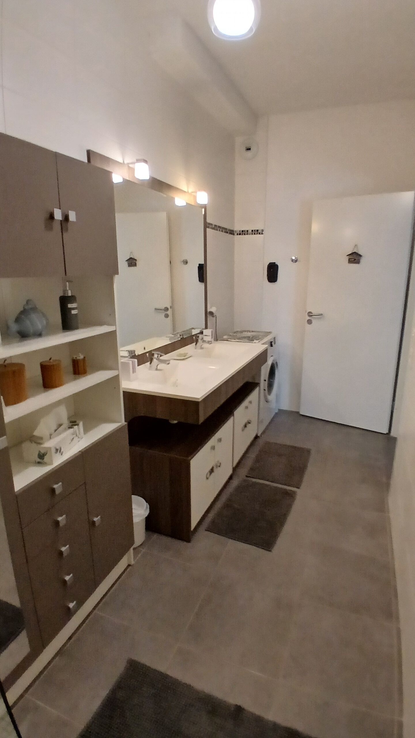 Een moderne badkamer met een grote spiegel, een wastafel, toilet en douchehoek.