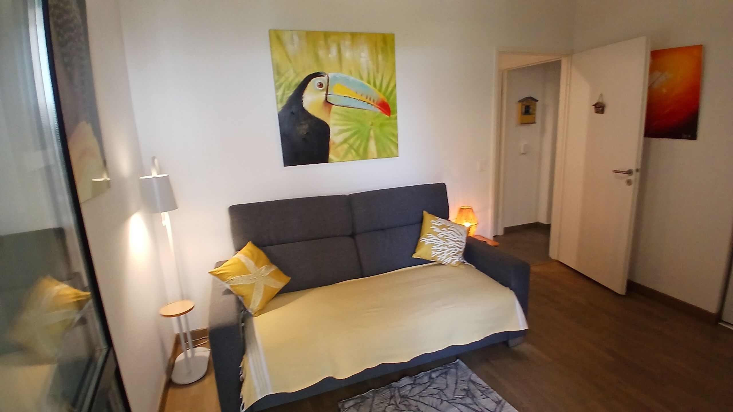 A room with a bed, a lamp, and a painting on the wall.