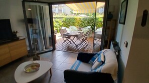 Habitación con puerta corrediza de vidrio que da a un patio exterior con mesa y sillas.
