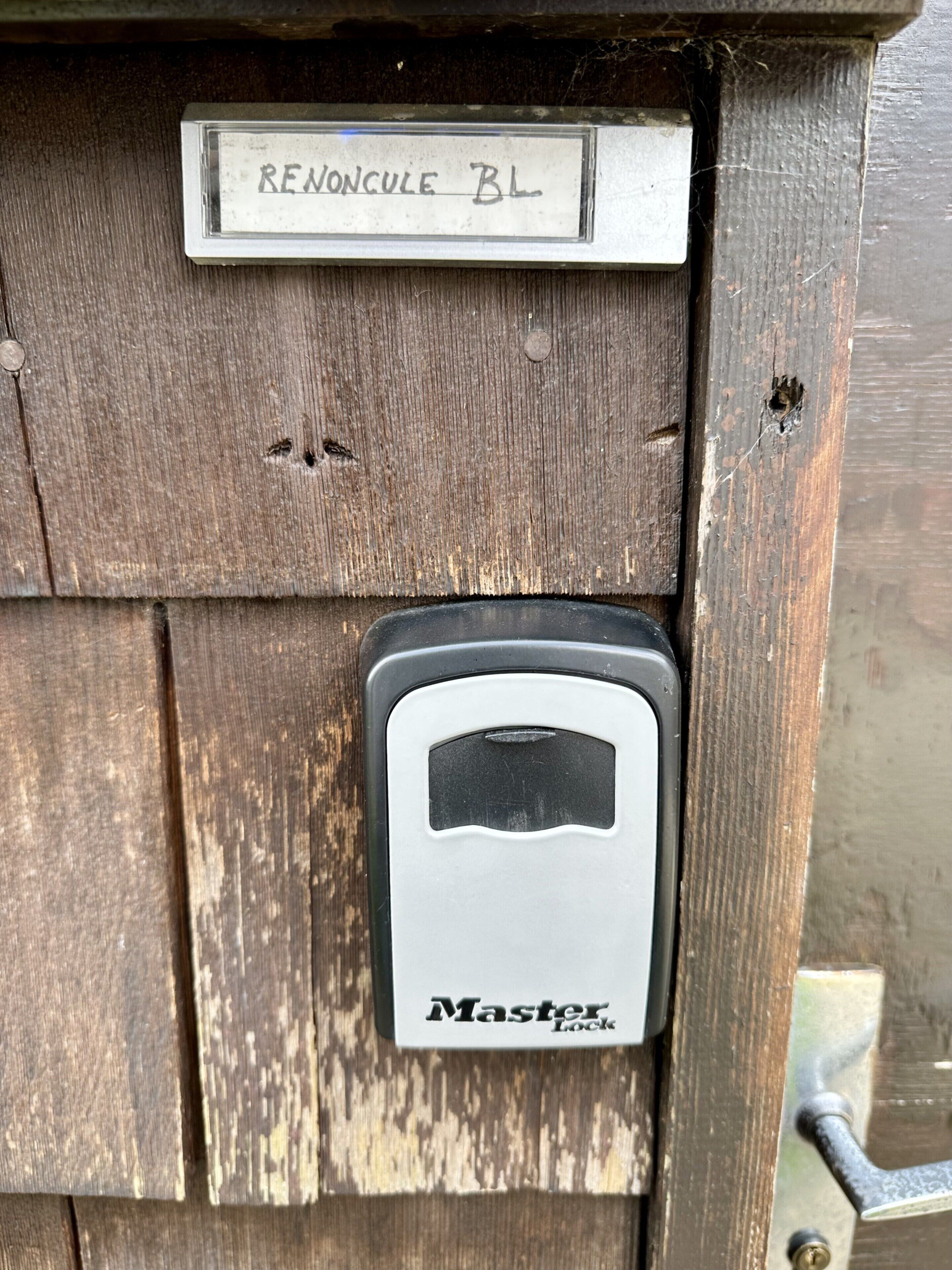 A wooden panel with a metal plaque labeled "RENONCULE BL" and a "Master Lock" device.