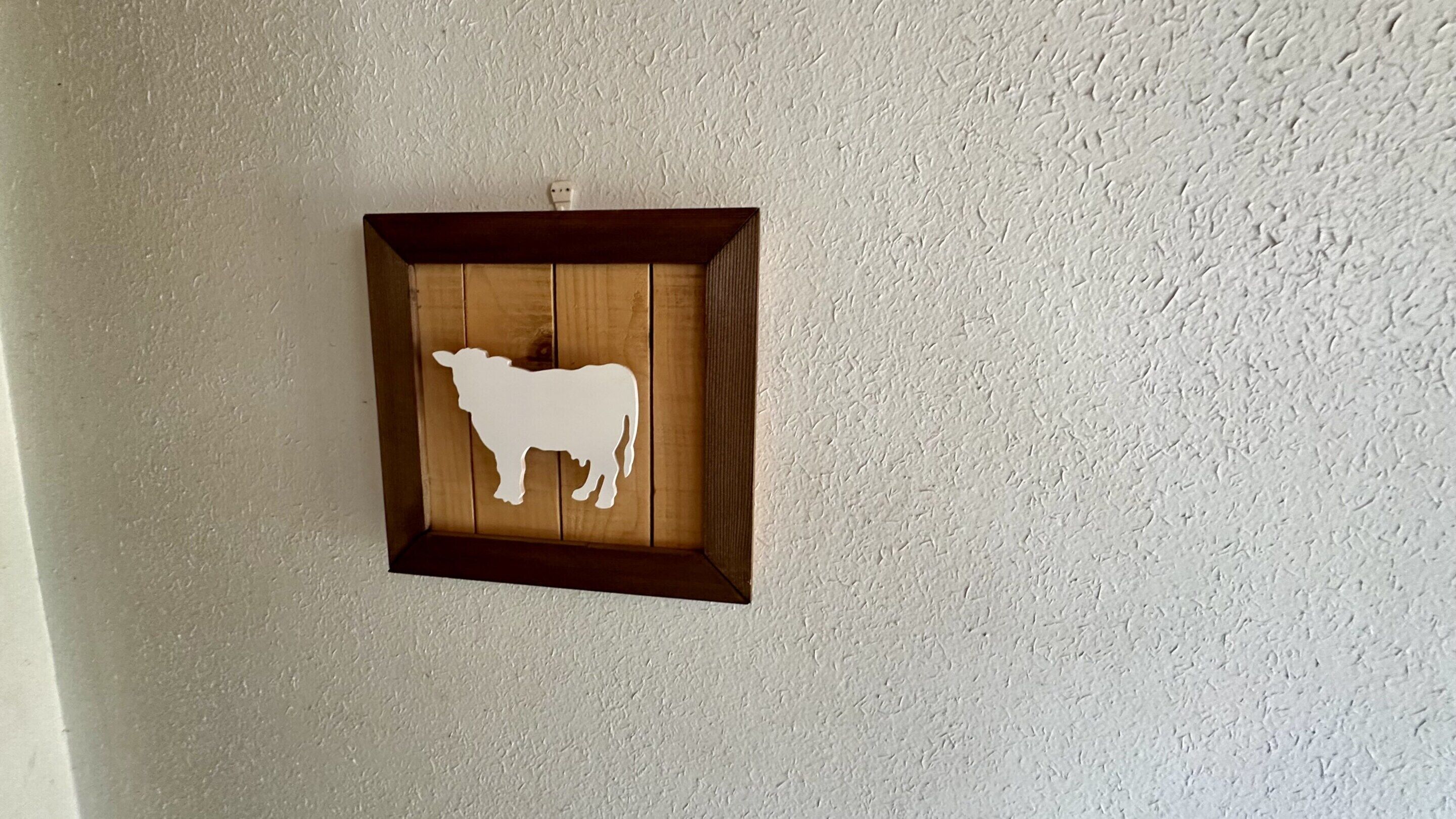 A wall-mounted wooden cutout of a cow.
