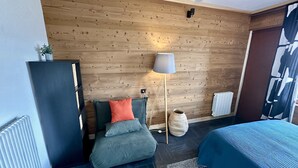 A modern room with a wooden wall, a floor lamp, a bed, a radiator, and a door with a geometric design. - Tranquil Flat for 5 in Murat-le-quaire (Murat-le-Quaire)