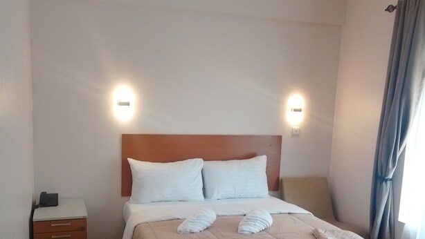 Ett hotellrum med en säng, sängbord och väggmonterade lampor.
