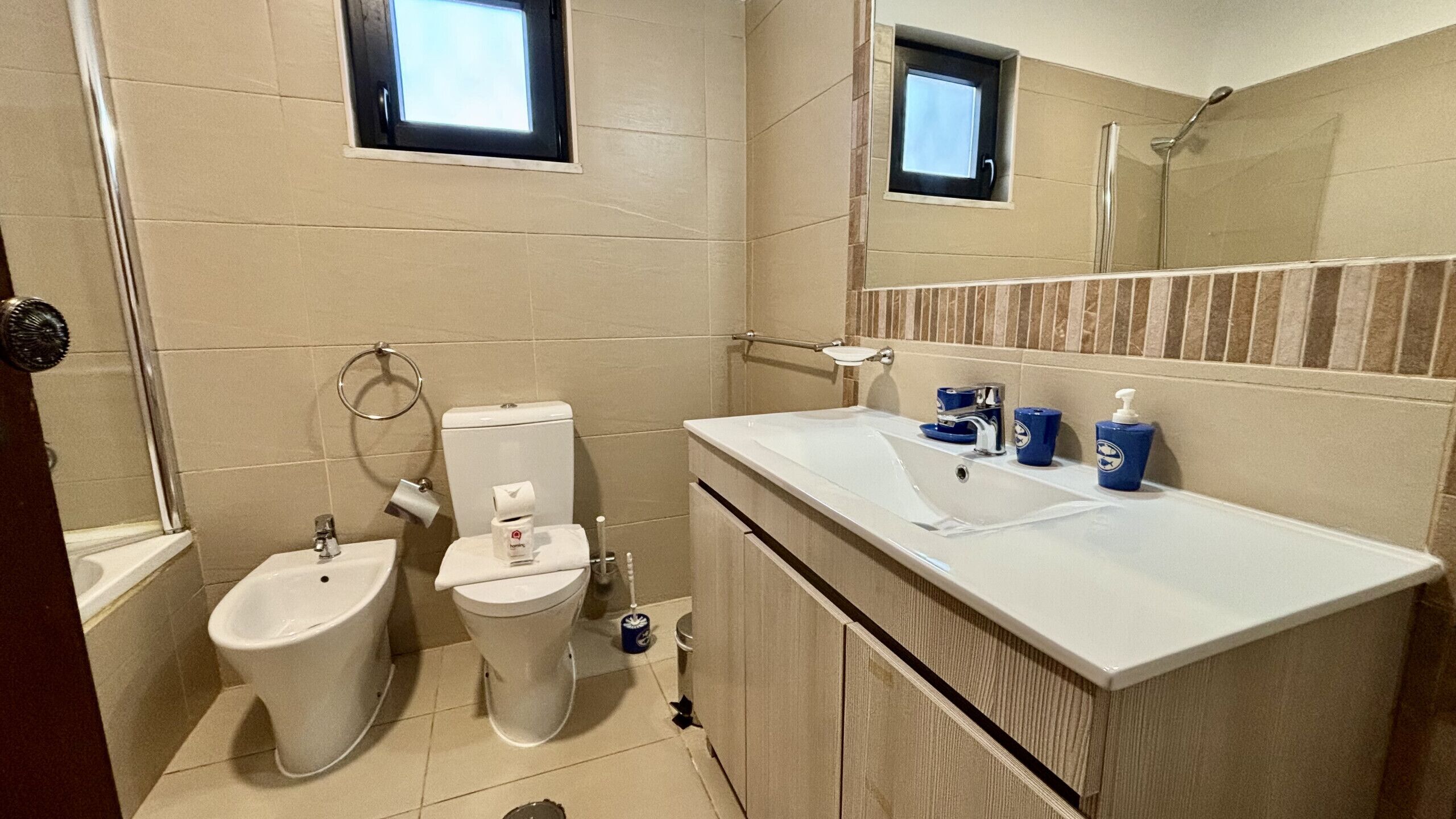 A bathroom with a bidet, toilet, sink, and mirror.