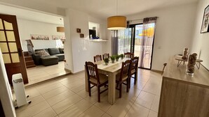 Een moderne eetruimte met een houten tafel en stoelen, een groot raam met gordijnen, en uitzicht op buiten.