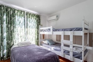 A room with a bunk bed, a single bed, and a window with curtains. - House Monet (Rio de Janeiro)