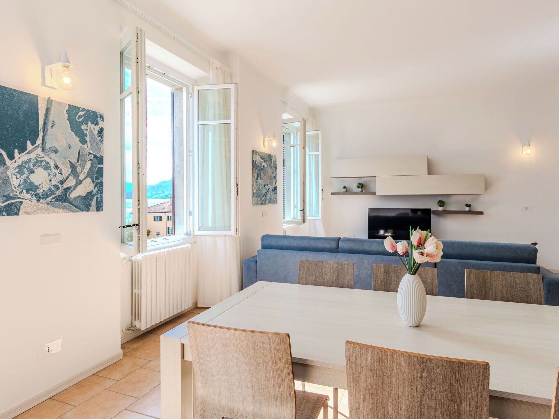 En moderne stue med sofa, spisebord med stole og fjernsyn.