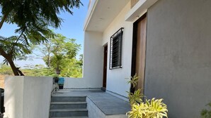 A modern building with a concrete staircase leading to a door. There are potted plants on the steps and along the wall. - Oasis Residency and Resorts  (Solapur)