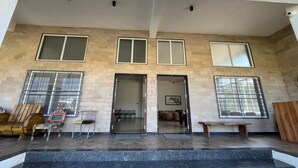 A building entrance with a set of steps leading up to a door, a bench, and a chair outside. - Oasis Residency and Resorts  (Solapur)