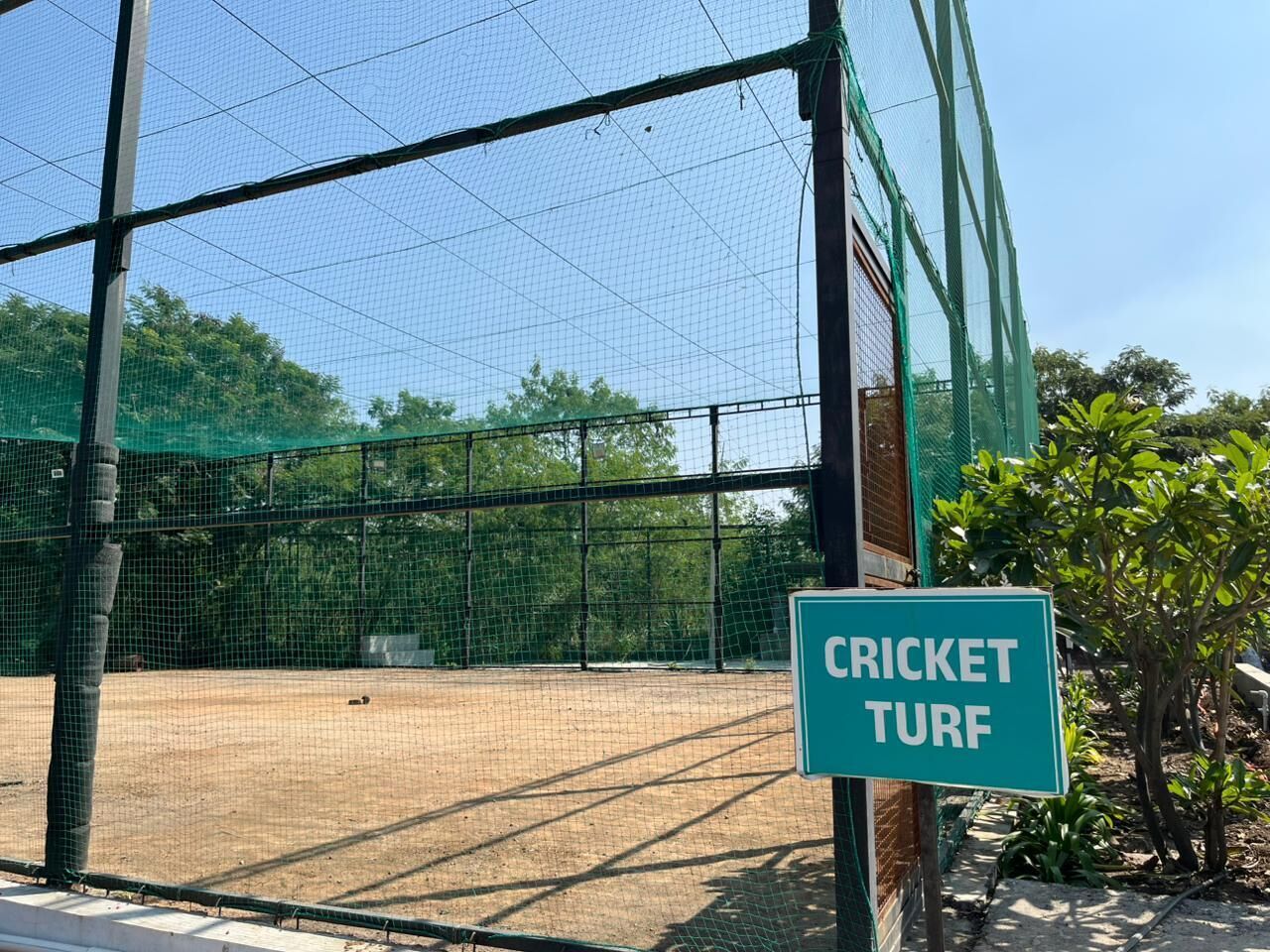 Campo de cricket con una barrera de malla y un letrero que indica que es un césped para cricket.