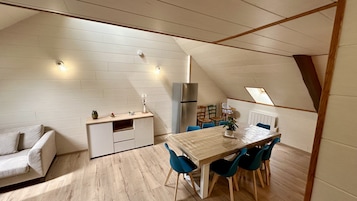 Una cocina compacta con comedor, piso de madera y techo inclinado.