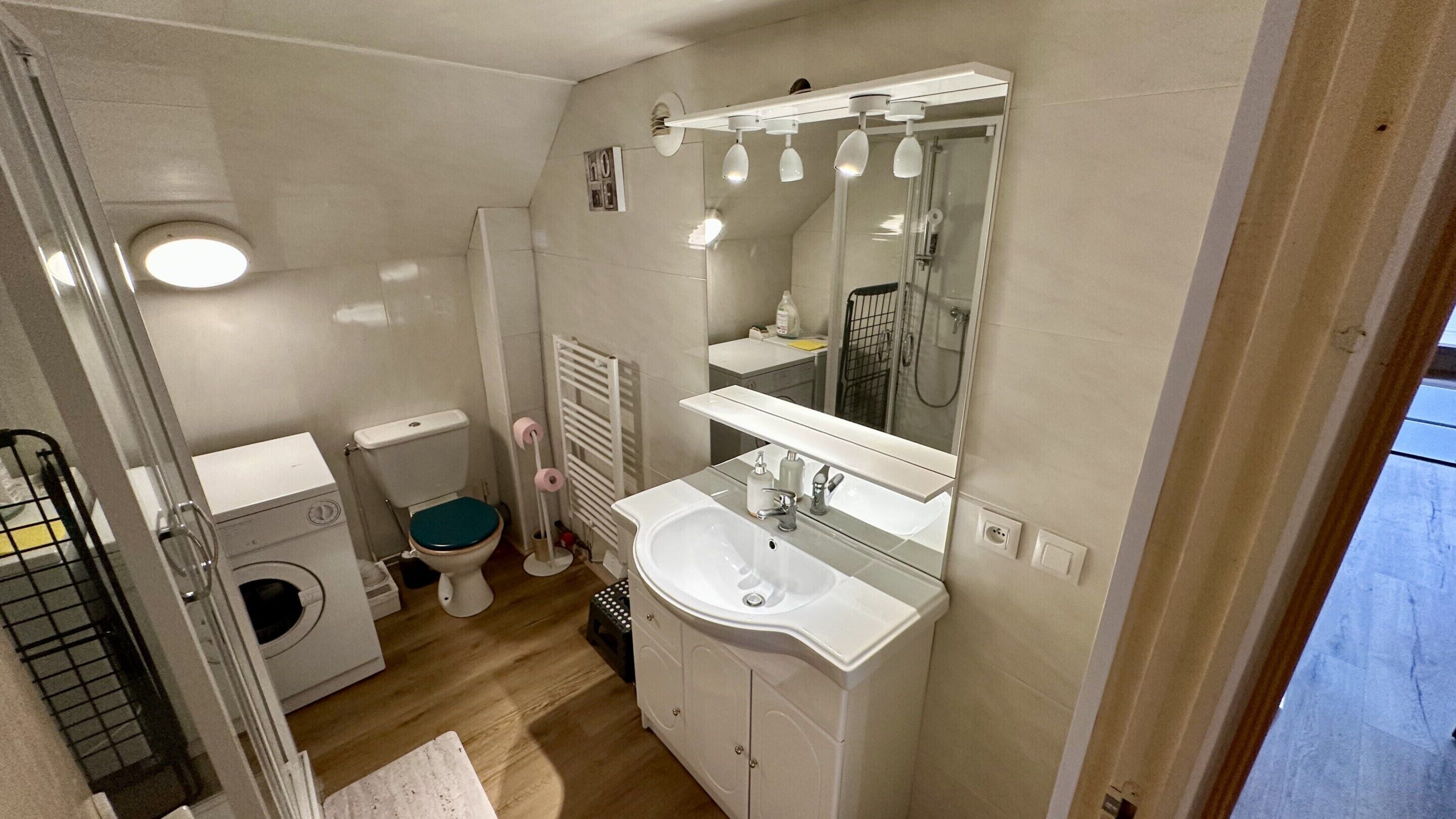 A compact bathroom with a toilet, sink, and shower.