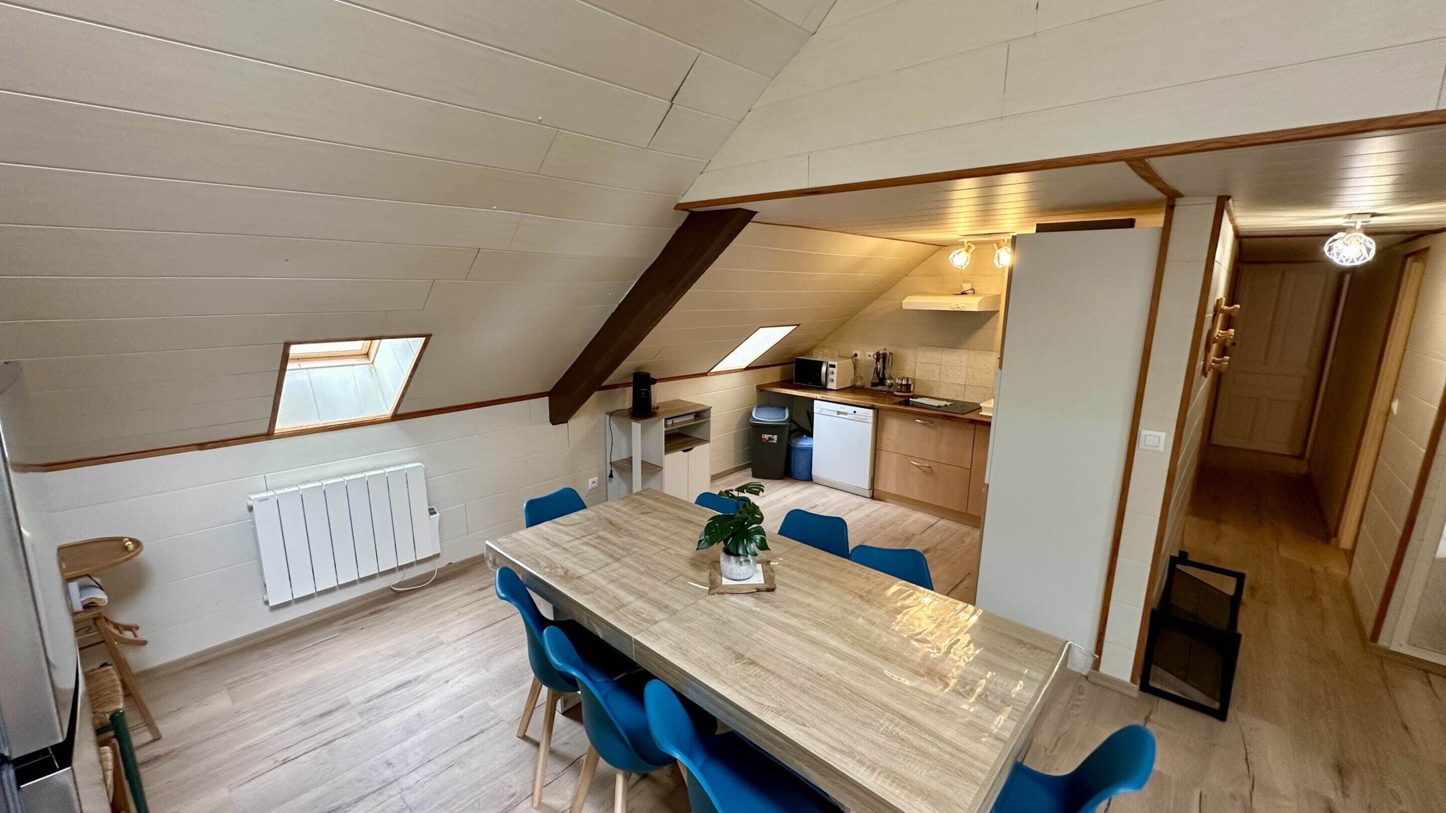 Eine kompakte, moderne Wohnung mit Essbereich, einer Küchenzeile und einem Schlafzimmer im oberen Bereich mit Dachfenstern.