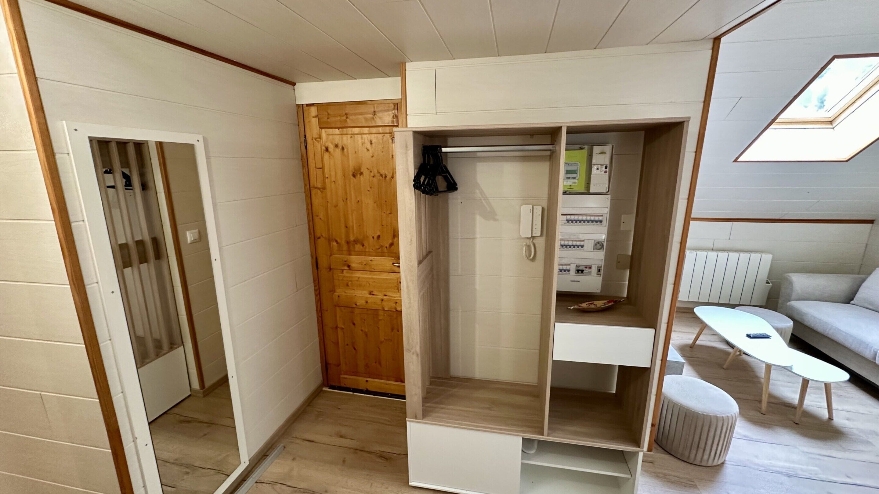 A compact room with a wooden wardrobe, a small table, and a sofa.