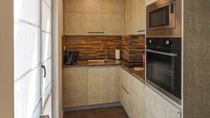 A compact kitchen with a built-in oven, a microwave, and a coffee maker on the counter. - Plovdiv City Centre One-Bedroom Apartment View Fully Equipped Kitchen City View (Plovdiv)