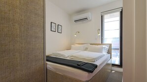 A hotel room with a bed, a bedside table, an air conditioning unit, and a window with a view. - Plovdiv City Centre One-Bedroom Apartment View Fully Equipped Kitchen City View (Plovdiv)