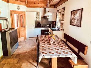 Een kleine keuken met een eettafel, een bankje en een plant in een pot.