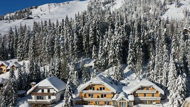 A snow-covered lodge with multiple buildings, surrounded by dense forest and a ski slope in the background. - Nice apartment for 4 guests with WIFI, TV, balcony and pets allowed (St Michael Im Lungau)