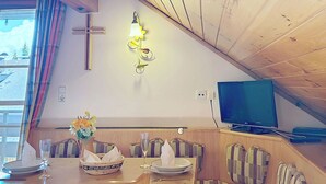 A dining area with a wooden table, benches, and a television on a stand. - Nice apartment for 4 guests with WIFI, TV, balcony and pets allowed (St Michael Im Lungau)