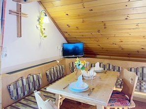 Ein gemütlicher Essbereich mit einem Holztisch, Bänken und einem Fernseher.