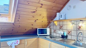 A kitchen with wooden cabinets, a microwave, a sink, and a window. - Nice apartment for 4 guests with WIFI, TV, balcony and pets allowed (St Michael Im Lungau)